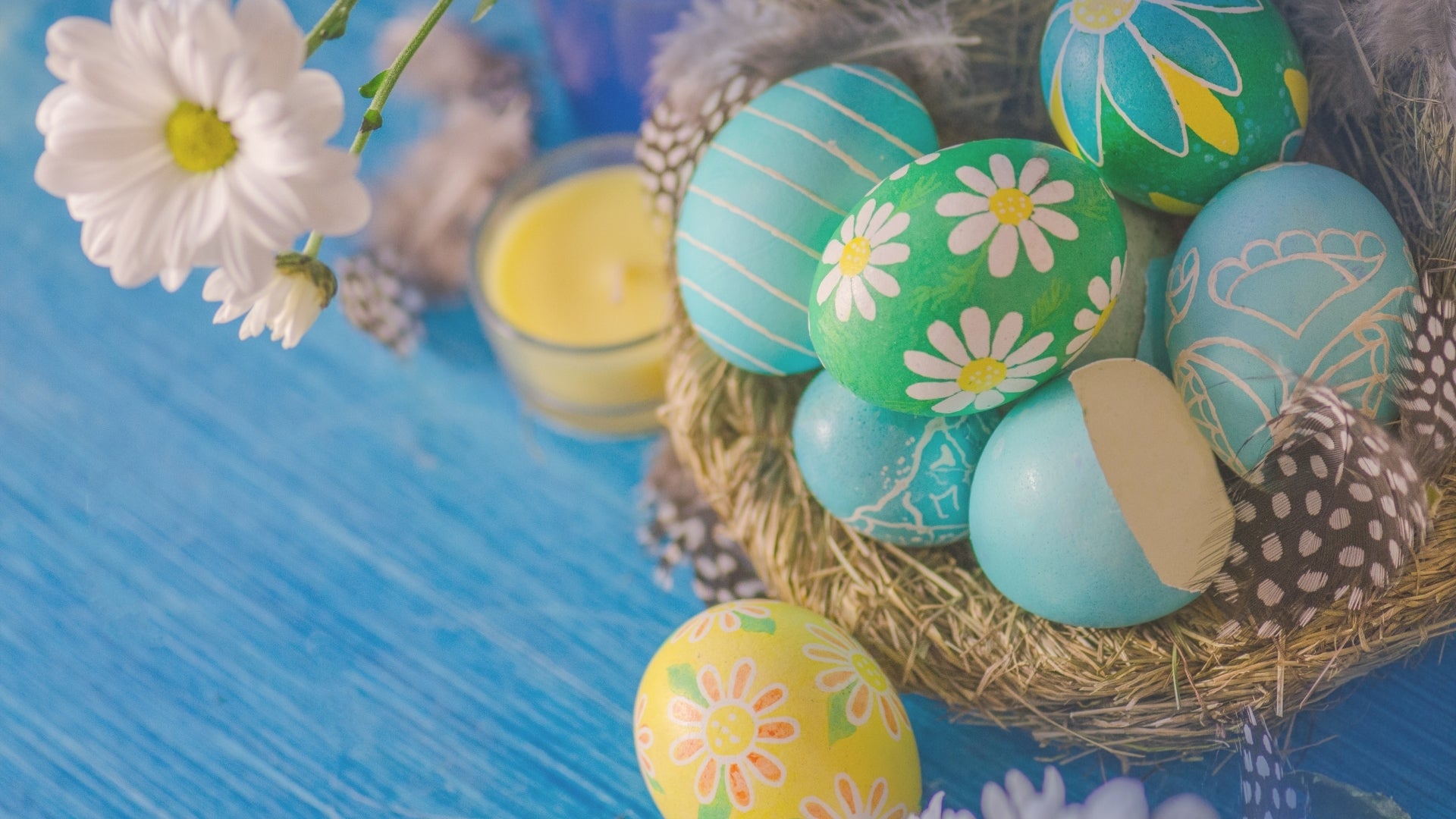 Decorative Easter eggs with floral patterns in a nest on a blue surface.
